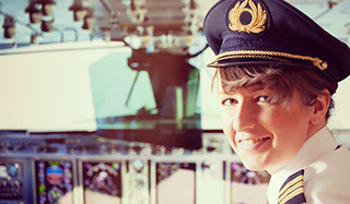 Woman pilot sitting in airplane cockpit smiling at camera